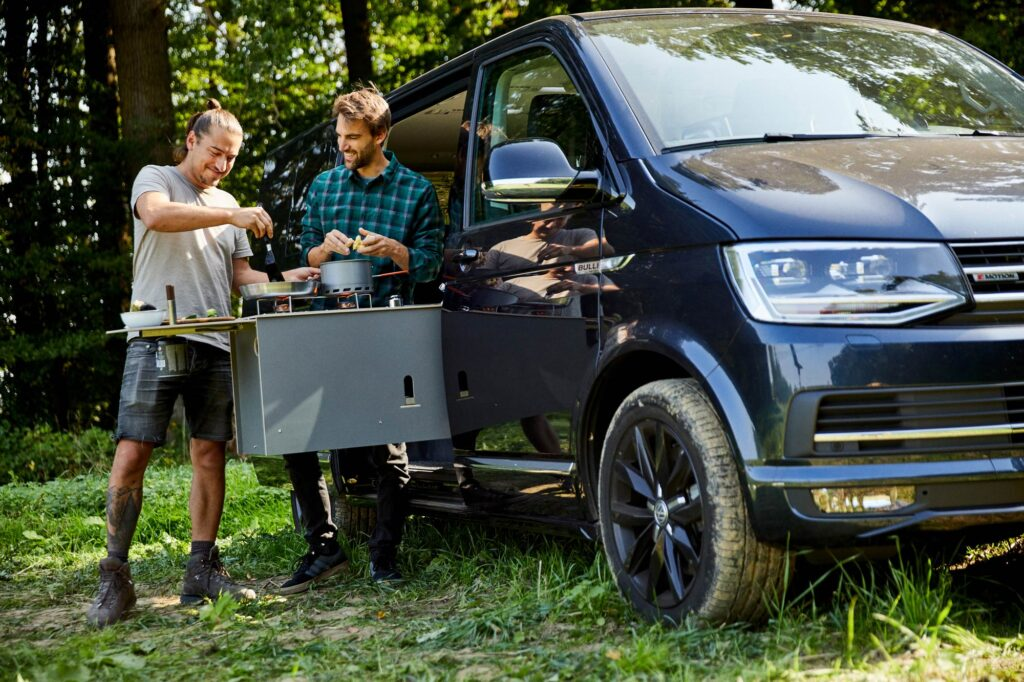 Zwei Personen mit Camptools-Ausrüstung am Auto