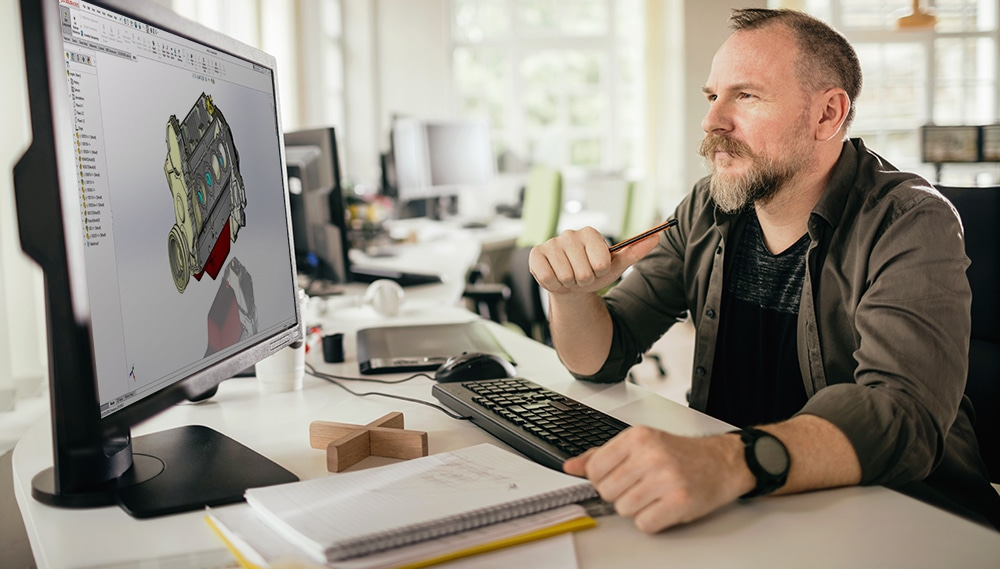 Mann sitzt am Schreibtisch mit Computer