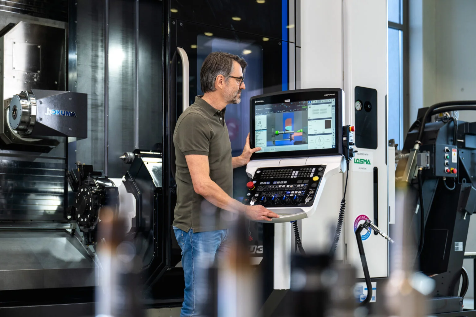 Ein Mann bedient oder überwacht eine CNC-Maschine in der Fertigung