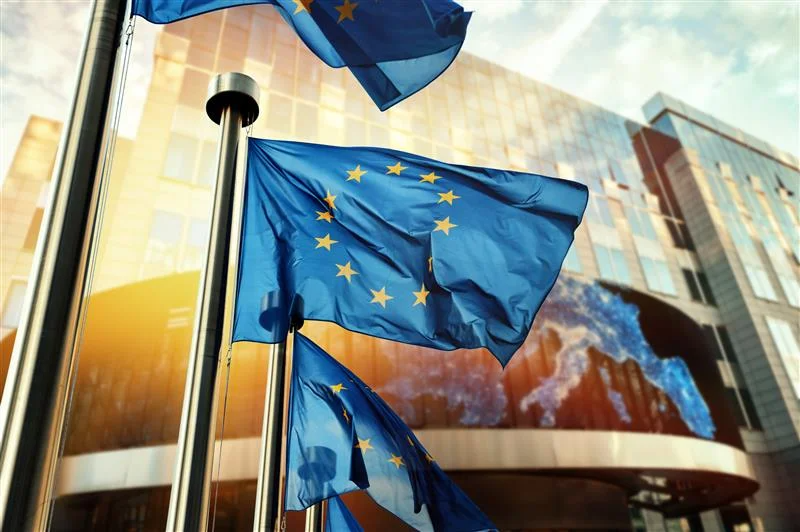 Mehrere Flaggen der Europäischen Union vor einem institutionellen Hintergrund