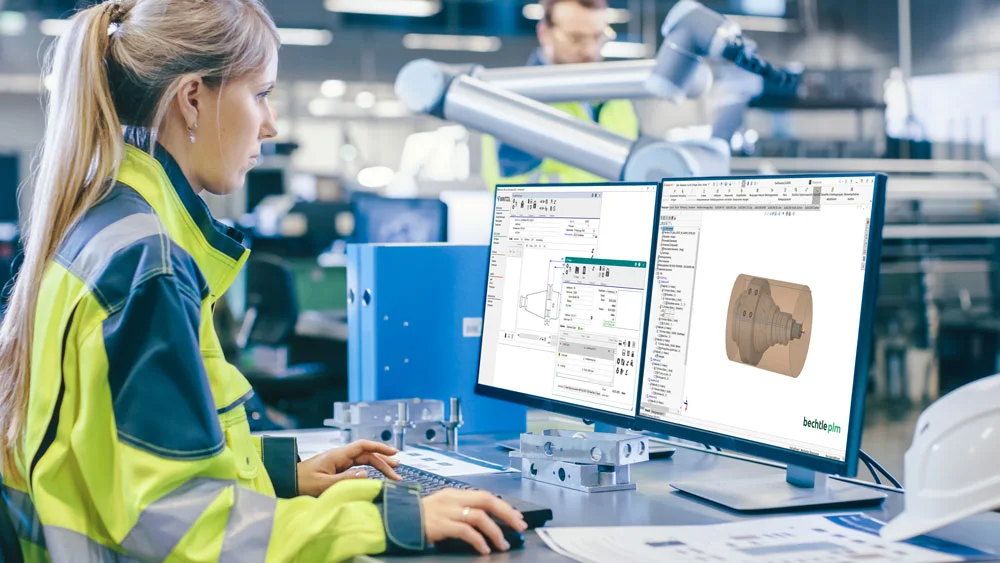 Eine Frau arbeitet in einer Fertigungshalle am PC zur Steuerung eines CNC-Prozesses